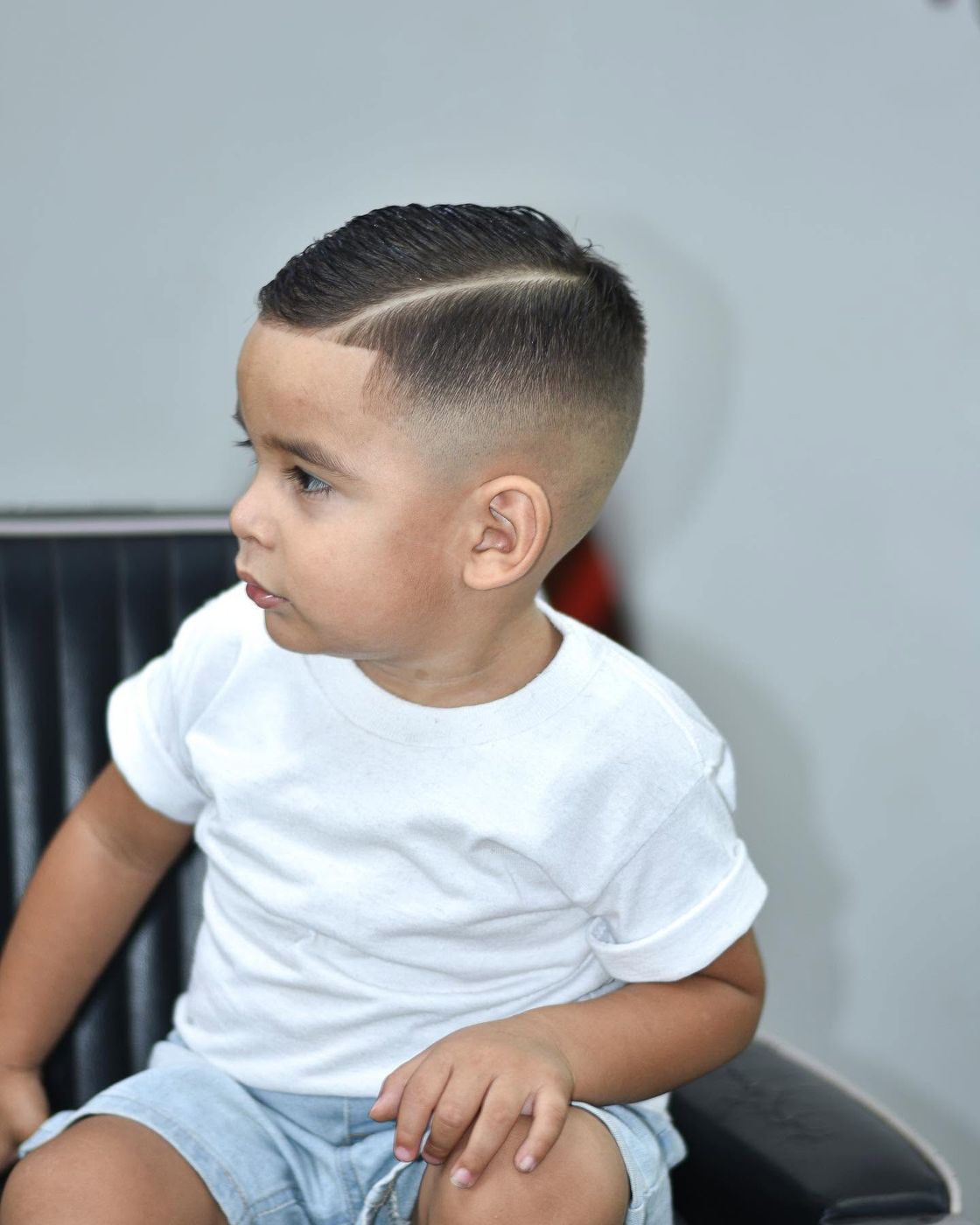 Niño sentado con corte clásico y raya marcada